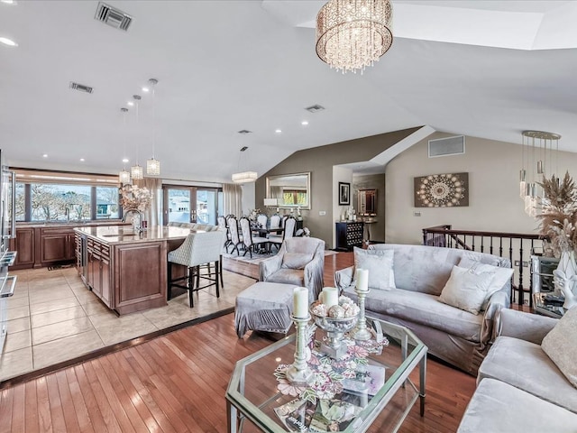 living room featuring lofted ceiling, light wood-type flooring, sink, and an inviting chandelier