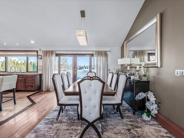 dining space featuring lofted ceiling, a healthy amount of sunlight, wood-type flooring, and french doors