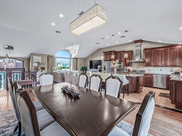 dining area with lofted ceiling, light wood-type flooring, and an inviting chandelier