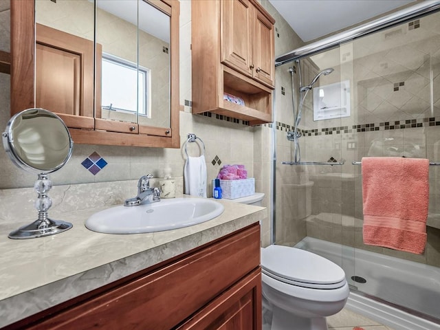 bathroom with backsplash, toilet, a shower with door, and vanity