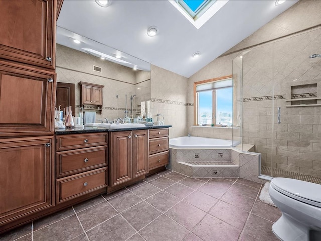 full bathroom with toilet, separate shower and tub, tile walls, lofted ceiling with skylight, and vanity