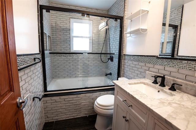 full bathroom with toilet, tile walls, enclosed tub / shower combo, and vanity