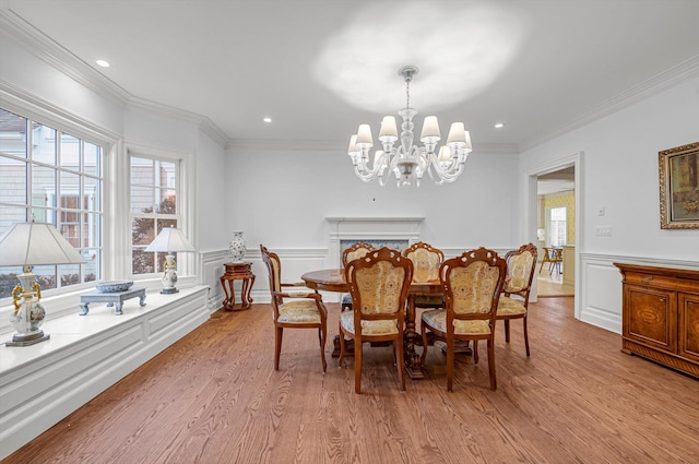 dining space with a wealth of natural light, light hardwood / wood-style flooring, crown molding, and an inviting chandelier