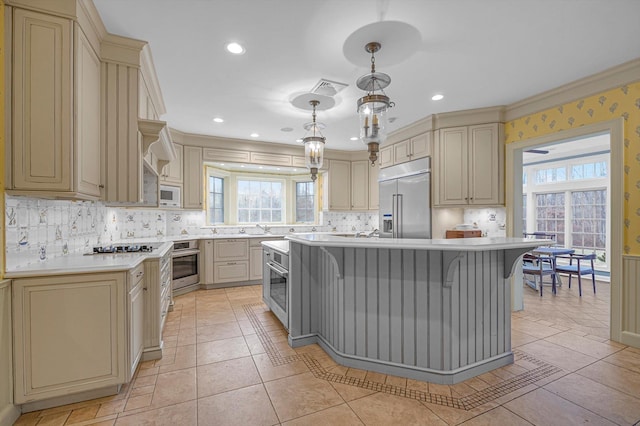 kitchen with decorative light fixtures, cream cabinetry, a center island, and built in appliances