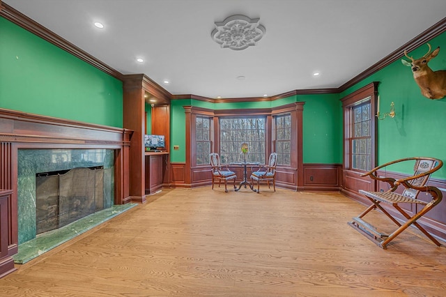 sitting room with light wood-type flooring, a high end fireplace, and crown molding