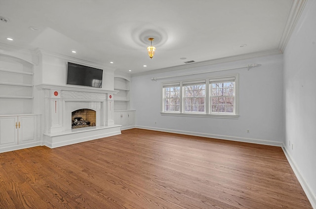 unfurnished living room with built in shelves, crown molding, and hardwood / wood-style flooring