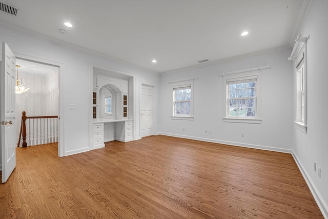 unfurnished bedroom featuring built in desk, a chandelier, ornamental molding, and light hardwood / wood-style floors