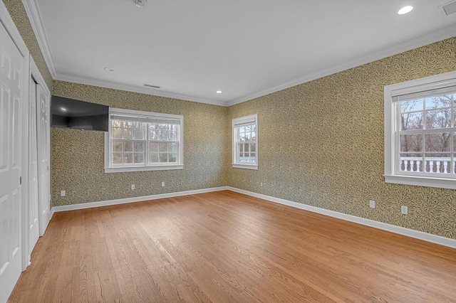 spare room with plenty of natural light, light hardwood / wood-style flooring, and crown molding