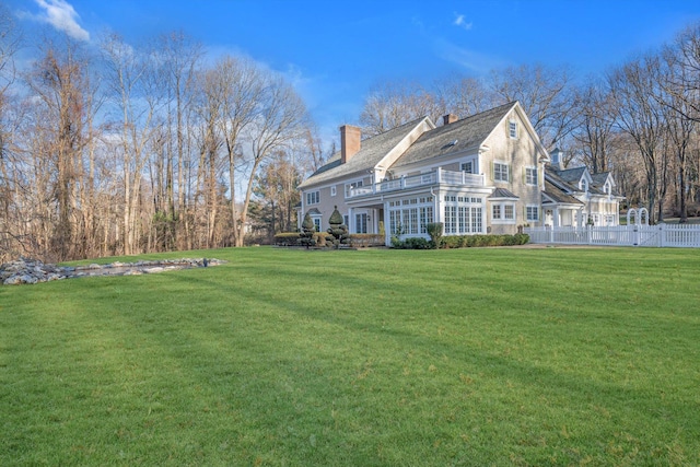 back of property with a balcony and a yard