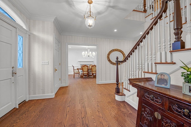 foyer entrance featuring a chandelier, ornamental molding, and hardwood / wood-style flooring