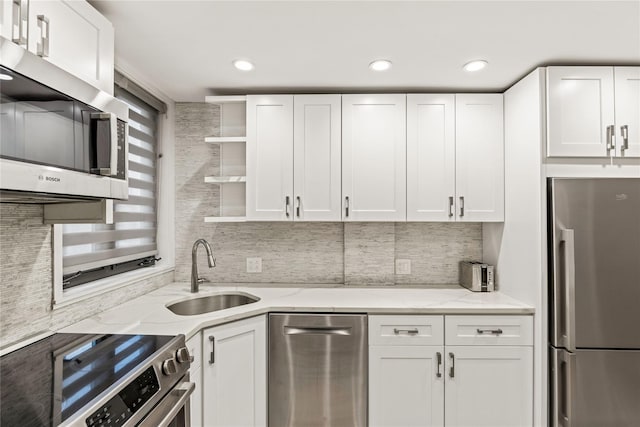 kitchen with light stone countertops, sink, white cabinetry, and stainless steel appliances