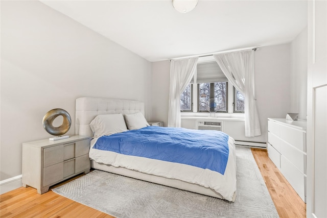 bedroom featuring baseboard heating, vaulted ceiling, an AC wall unit, and light hardwood / wood-style flooring