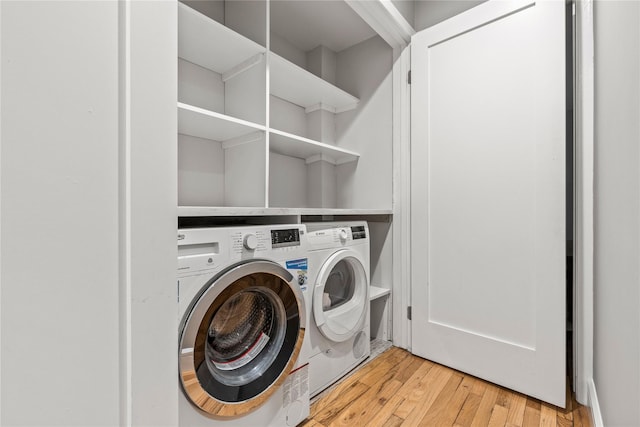 laundry room with separate washer and dryer and light hardwood / wood-style floors