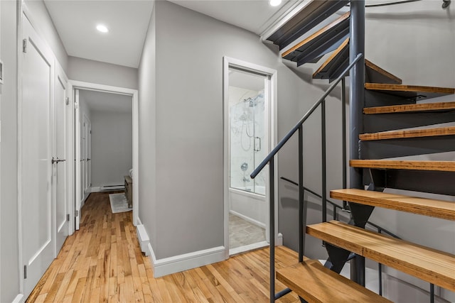 stairway featuring baseboard heating and hardwood / wood-style floors