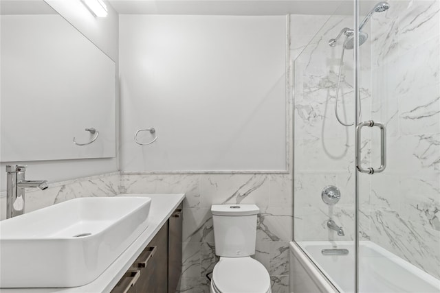 full bathroom featuring toilet, tile walls, vanity, and shower / bath combination with glass door