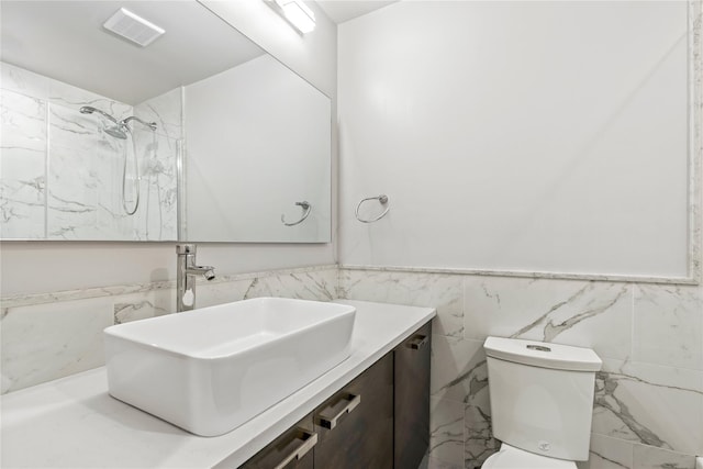 bathroom featuring a shower, tile walls, toilet, and vanity