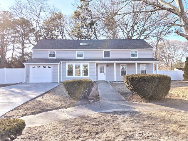 traditional home featuring a garage, concrete driveway, roof with shingles, and fence