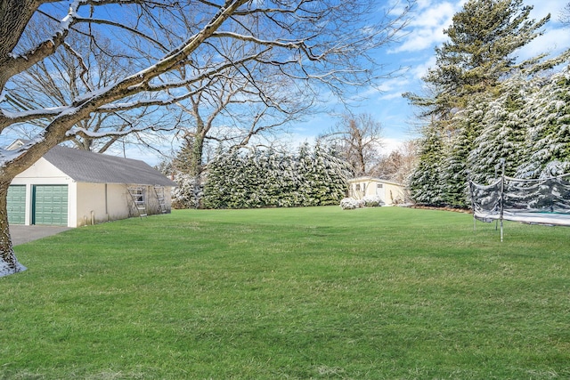 view of yard with a garage, an outbuilding, and a trampoline