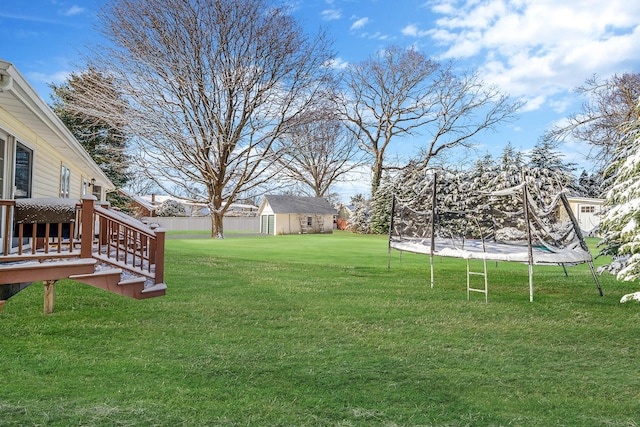 view of yard with a storage unit, a deck, and a trampoline