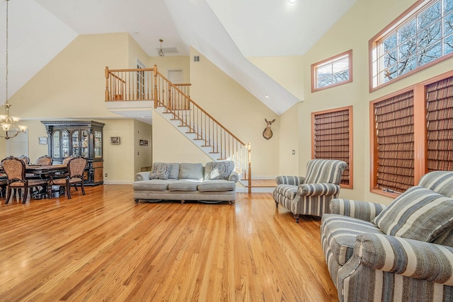 living room featuring light wood-type flooring, a chandelier, and a high ceiling