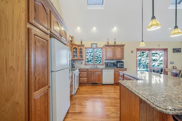 kitchen featuring white appliances, light stone countertops, hanging light fixtures, decorative backsplash, and sink