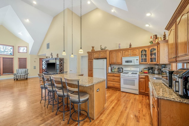 kitchen featuring white appliances, a center island, decorative light fixtures, a skylight, and high vaulted ceiling