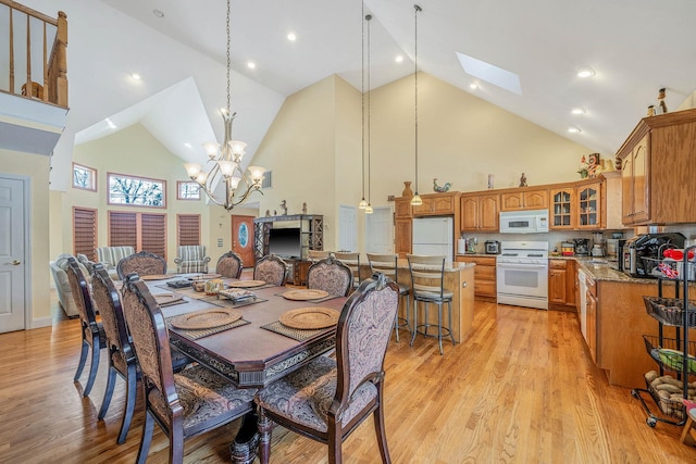 dining area with a notable chandelier, a skylight, high vaulted ceiling, and light hardwood / wood-style flooring