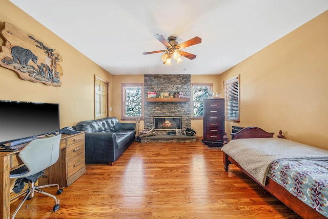 bedroom with ceiling fan, hardwood / wood-style flooring, and a fireplace