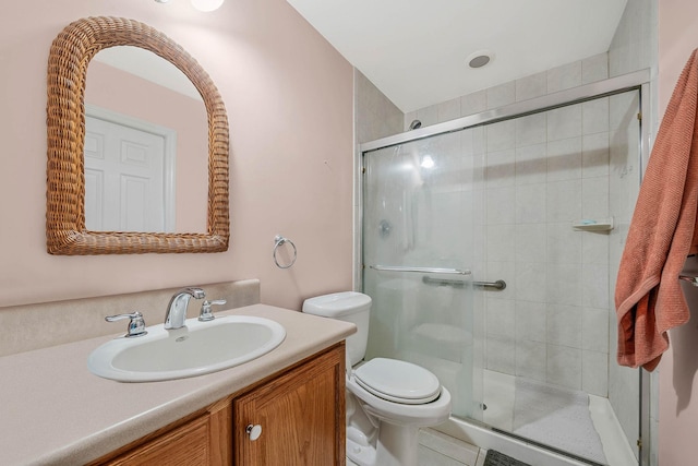 bathroom featuring toilet, vanity, and an enclosed shower