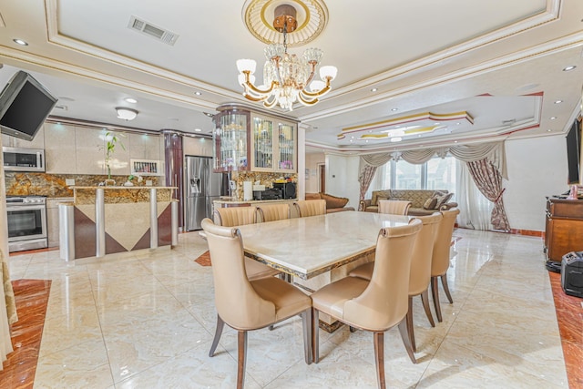 dining area with crown molding, a notable chandelier, and a tray ceiling