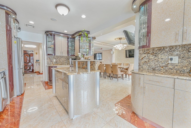 kitchen with stainless steel fridge, hanging light fixtures, a center island, tasteful backsplash, and light stone countertops