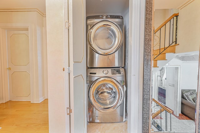 clothes washing area featuring stacked washer and dryer and light wood-type flooring