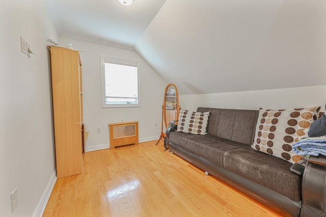 living room featuring vaulted ceiling, ornamental molding, and light wood-type flooring