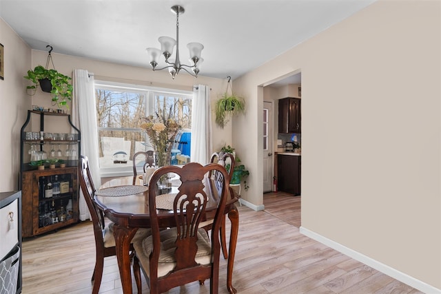 dining area with an inviting chandelier, beverage cooler, and light wood-type flooring