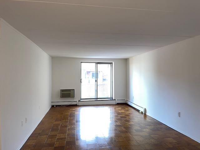 unfurnished room featuring a baseboard heating unit, dark parquet floors, and an AC wall unit