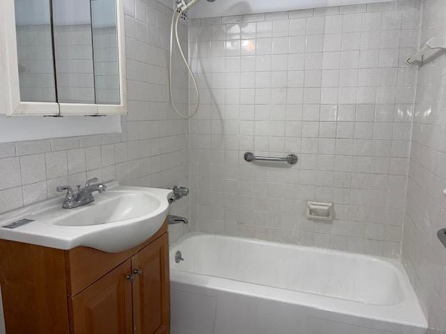 bathroom featuring tiled shower / bath, vanity, and decorative backsplash