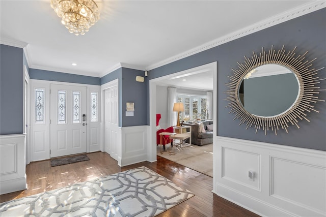 entrance foyer with wood finished floors, wainscoting, crown molding, and an inviting chandelier