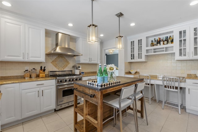 kitchen featuring wall chimney exhaust hood, light tile patterned flooring, premium stove, and white cabinetry