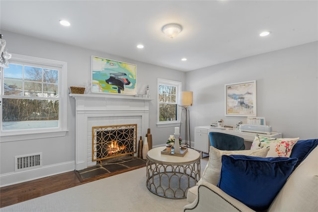 sitting room with visible vents, baseboards, wood finished floors, a lit fireplace, and recessed lighting