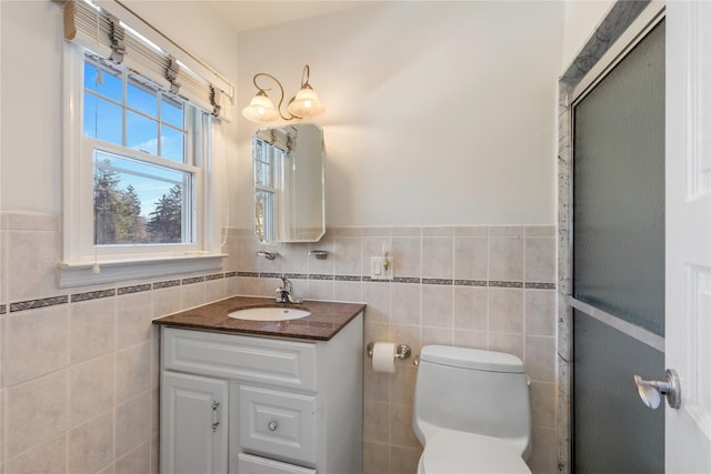 bathroom with toilet, a wainscoted wall, tile walls, and vanity