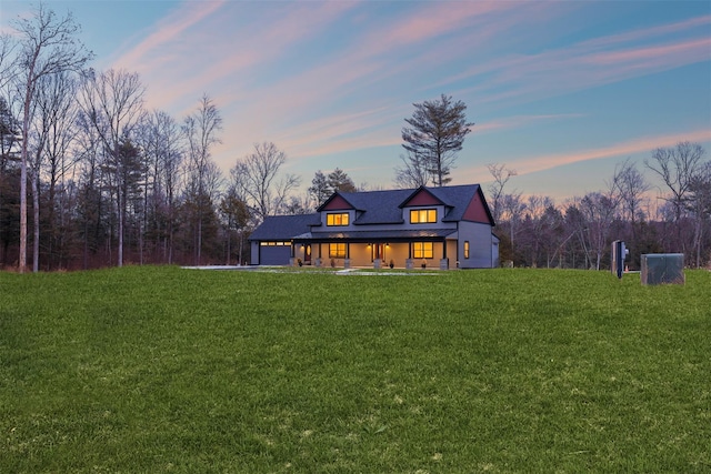 back house at dusk with a garage and a lawn