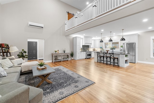 living room with a high ceiling, light hardwood / wood-style floors, and a wall unit AC