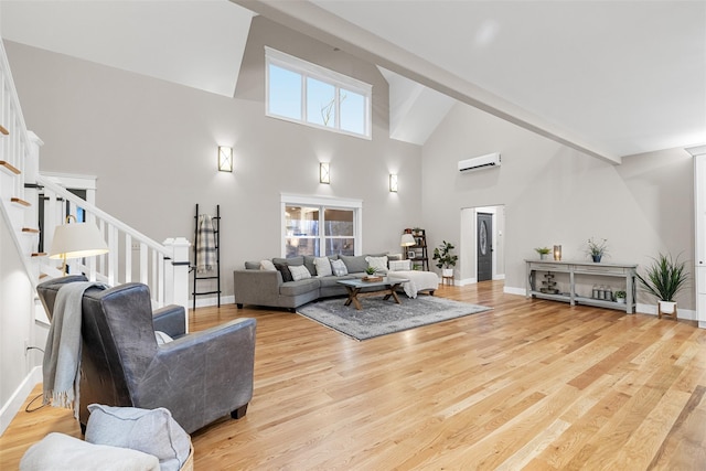 living room featuring high vaulted ceiling, light hardwood / wood-style flooring, and a wall mounted AC