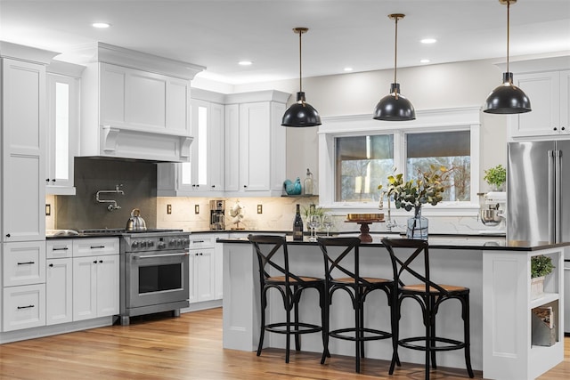 kitchen with high end stainless steel range oven, white cabinets, a breakfast bar, and a center island