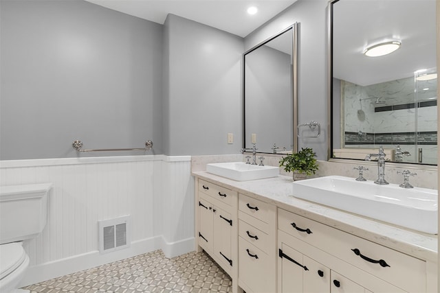 bathroom featuring toilet, a shower with door, and vanity