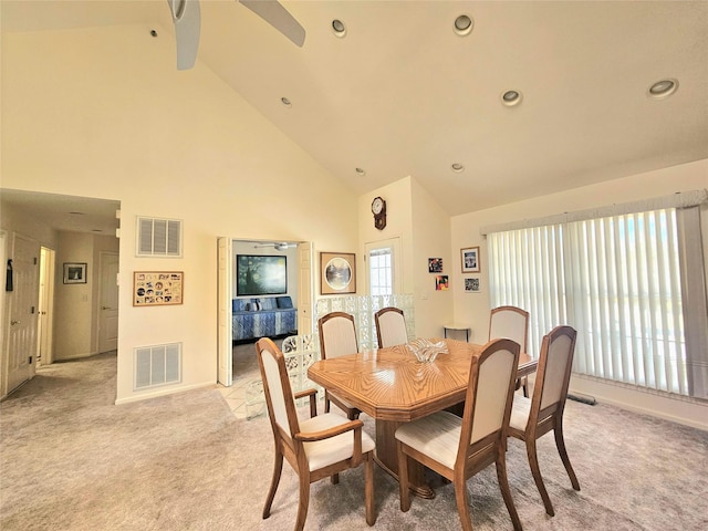 dining room with ceiling fan, light colored carpet, and high vaulted ceiling