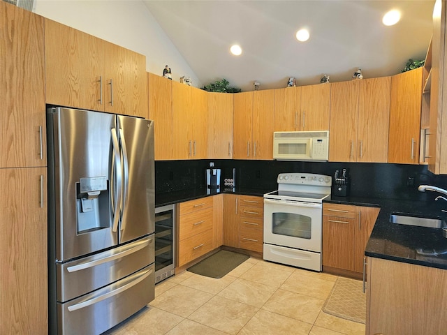 kitchen with lofted ceiling, sink, light tile patterned floors, white appliances, and beverage cooler