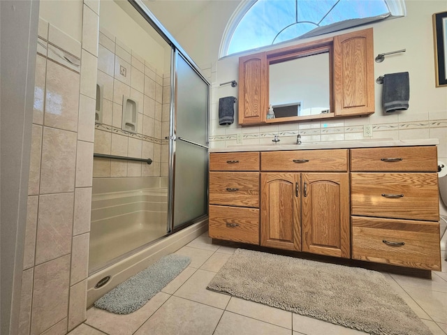 bathroom featuring tasteful backsplash, vanity, a shower with door, and tile patterned flooring