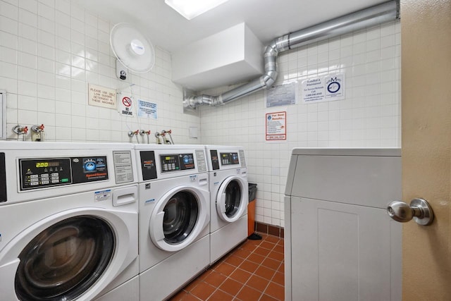 laundry area with washer and dryer, tile walls, and dark tile patterned floors