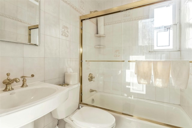 full bathroom with toilet, bath / shower combo with glass door, tile walls, and sink